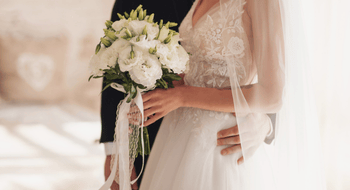 a bride holding wedding boquet and groom embracing each her